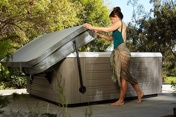 A lady demonstrates one person operation of a hot tub cover lifter on her back patio